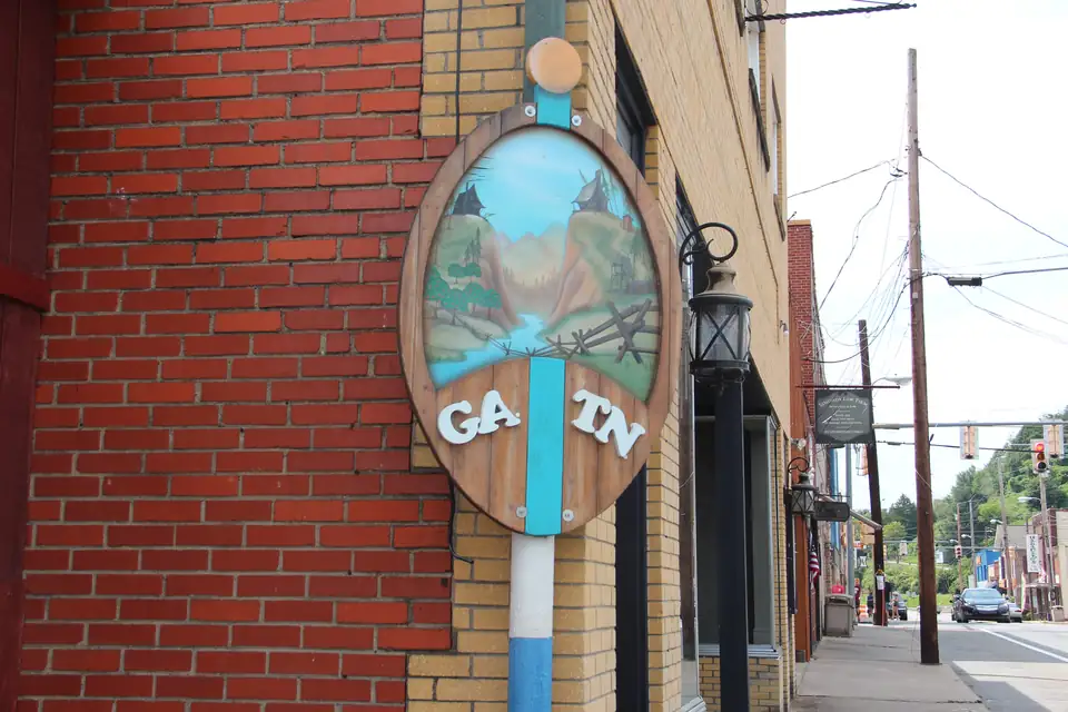 Oval painted sign reading 'GA. TN' split by a blue stripe, mounted on a brick building beside a lantern and sidewalk